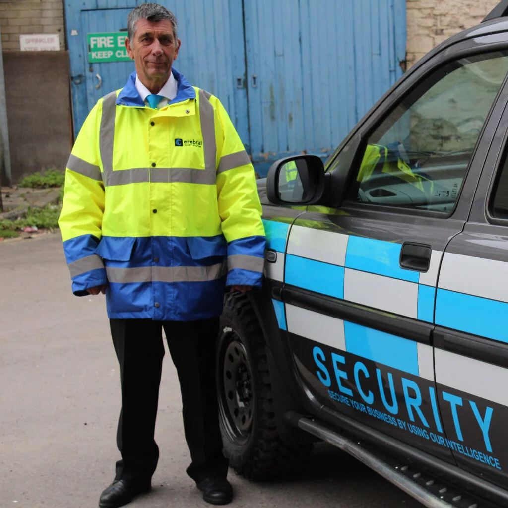 Security guard standing next to vehicle. Cerebral Security Solutions. Security Guarding, Door Supervisors, Hotel Security, Keyholding, Mobile Security, Vacant Property Security, Farm Security, Education Security. Bristol, Somerset.